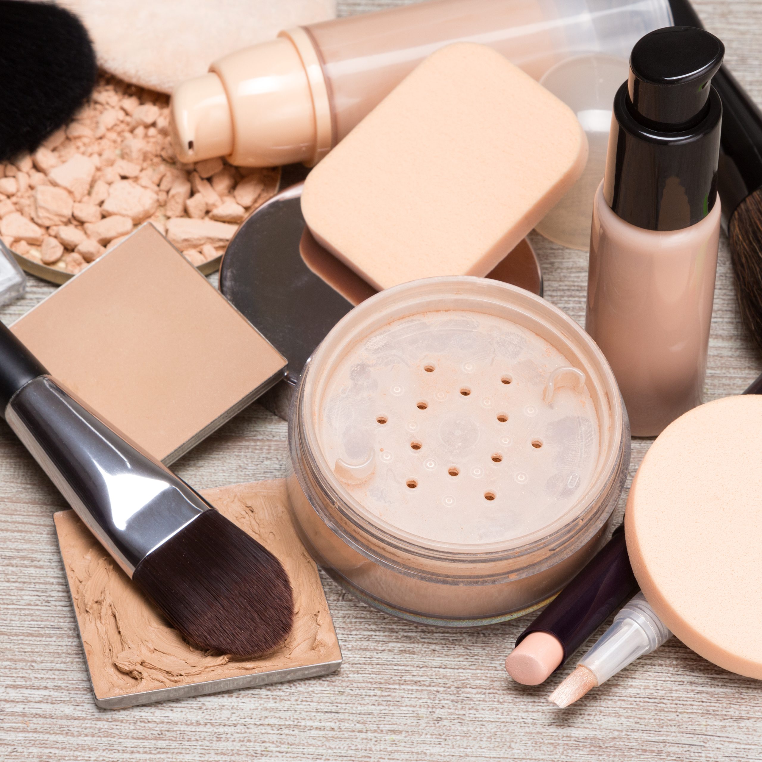 Concealers, bottles of liquid foundation, loose and compact powder, makeup brushes